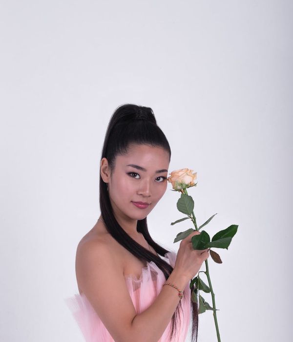 A serene woman in a yoga pose against a dark background with pink light accents.